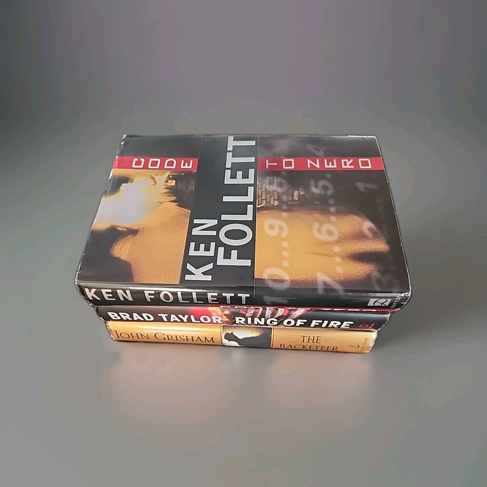 Lot of 3 Brad Taylor, Ken Follett and John Grisham hardcover books As Shown